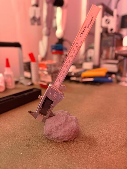 A set of digital calipers stuck in a fake 3-D printed rock like the sword in the stone. 