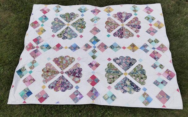 a quilt, it is 4 wheels of fabric on a light background, the wheels divided into 4 sections, diamond designs running between them 