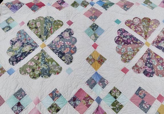 a close-up of a region of the face of the quilt, lots of pinks and blues and some yellow and purple 