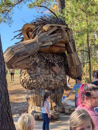 A 12 feet wood sculpture of a troll, covering his eyes