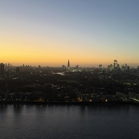 A photo of the London skyline, facing west, taken from a high-rise apartment building in Canary Wharf east London. The river Thames is in the foreground and in the middle ground we can see both Tower Bridge and The Shard. 