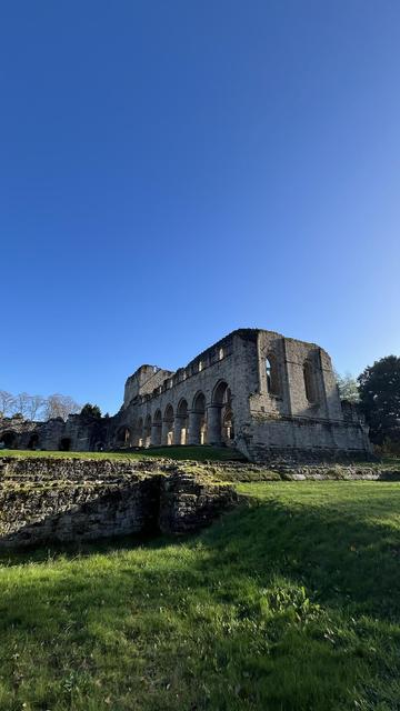 An exterior shot of the ruins of Buildwas Abbey, taken facing east.  The sky is clear and blue, green grass is visible in the foreground. 