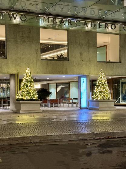 two Christmas trees lit in white twinkle lights outside Embarcadero Center in San Francisco