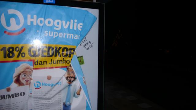 in een bushokje is de supermarkt reclame aan de kant geduwd voor een groene diefstal
mooi meegenomen sticker