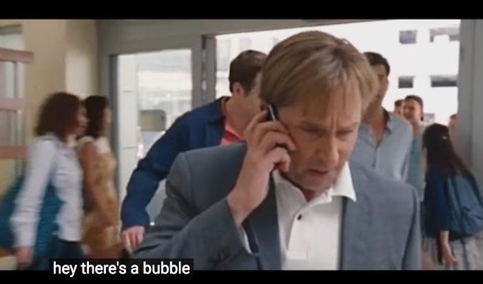 A man in a suit is speaking on a phone while looking concerned. He is surrounded by people in a busy indoor setting. The caption at the bottom reads, "hey there's a bubble."
