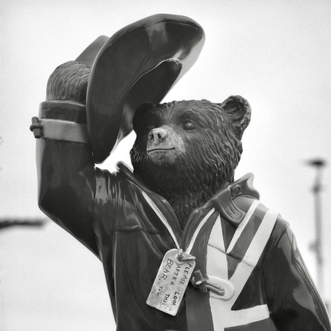 A black-and-white film photo. The statue of Paddington Bear, dressed up and raising his hat, looks out at the city in Lima, Peru. Friday, September 26, 2025.
