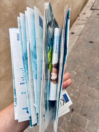 Folletos publicitarios fotografiados con el piso de una acera de fondo.