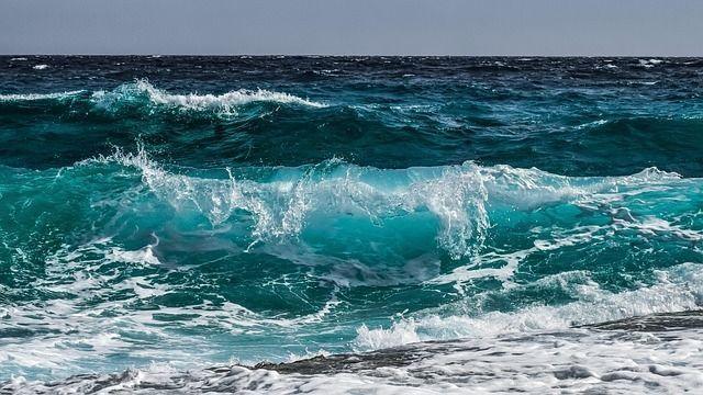 Blue water waves crashing on a coastline.