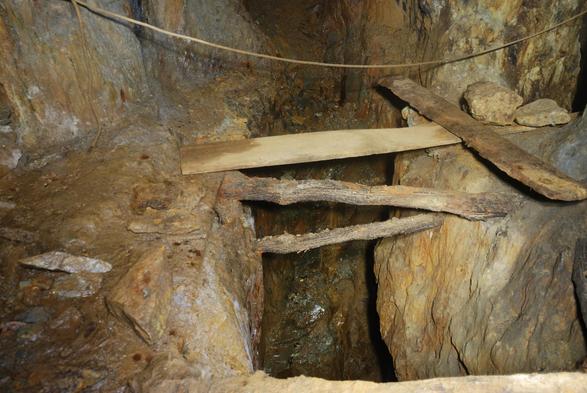 Plank bridging a deep winze in the adit floor. A rope provides some reassurance to those brave enough to cross over the 120 foot-deep hole! Stope workings lie out of shot on the upper right.