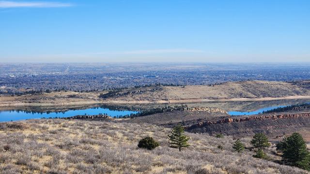 A narrow reservoir tucked between rocky ridges, reflecting blue sky and the same ridges.