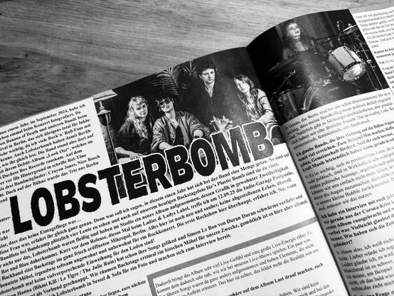 A black and white magazine spread featuring an article about the band "Lobsterbomb." The large text of the band's name is prominently displayed, with images of the band members sitting together. The accompanying text discusses their music and experiences.