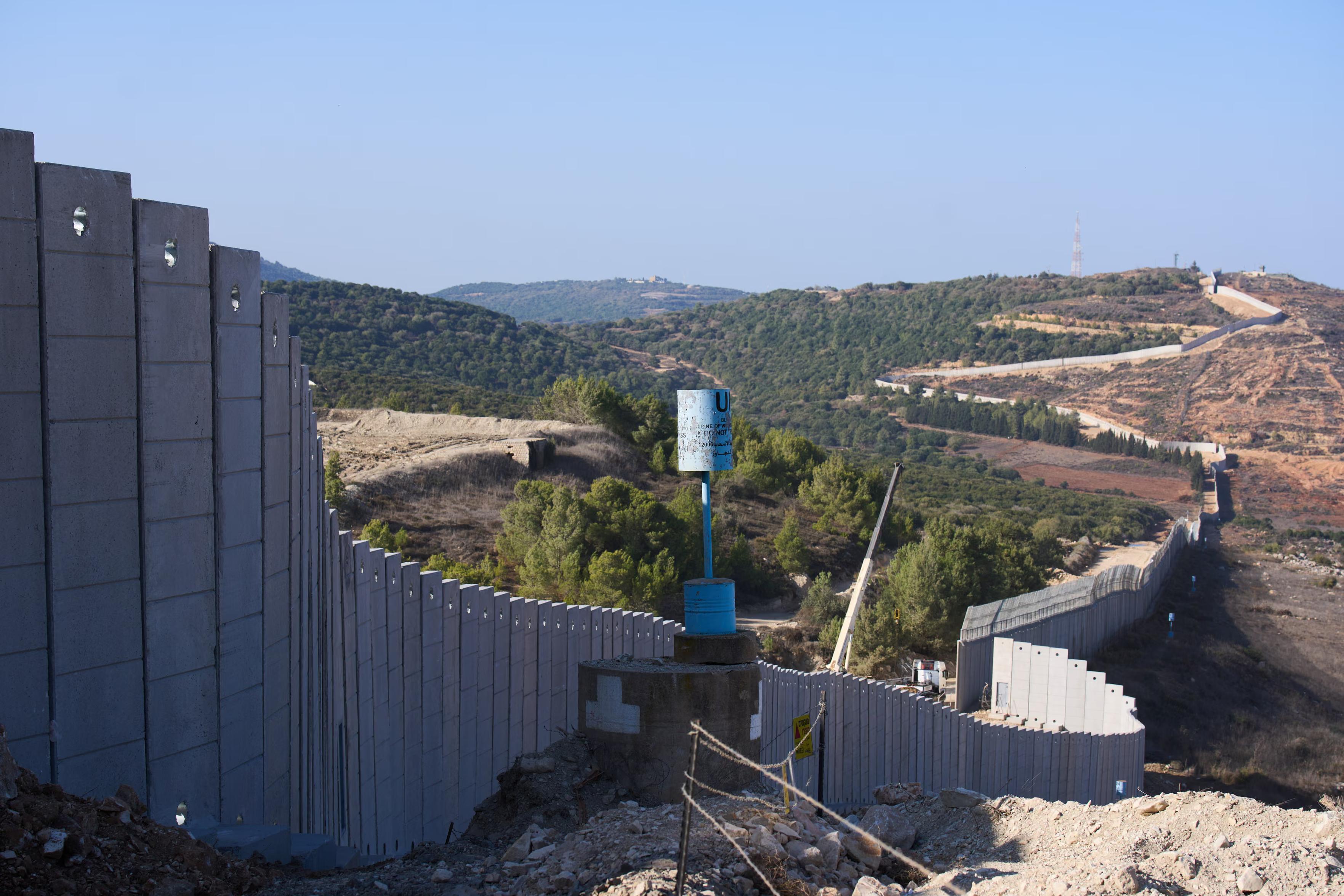 A blue line marker stands near a concrete wall constructed by Israel at its frontier with Lebanon.