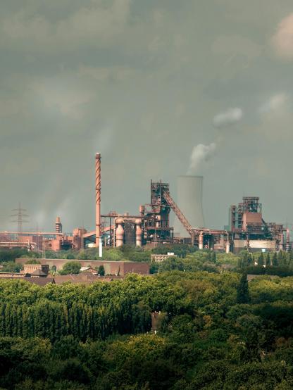 a photo of a factory polluting the environment around it and spewing hot gases into the air. 