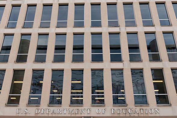 The exterior of the U.S. Department of Education building, showing rows of tall windows set in a beige facade.