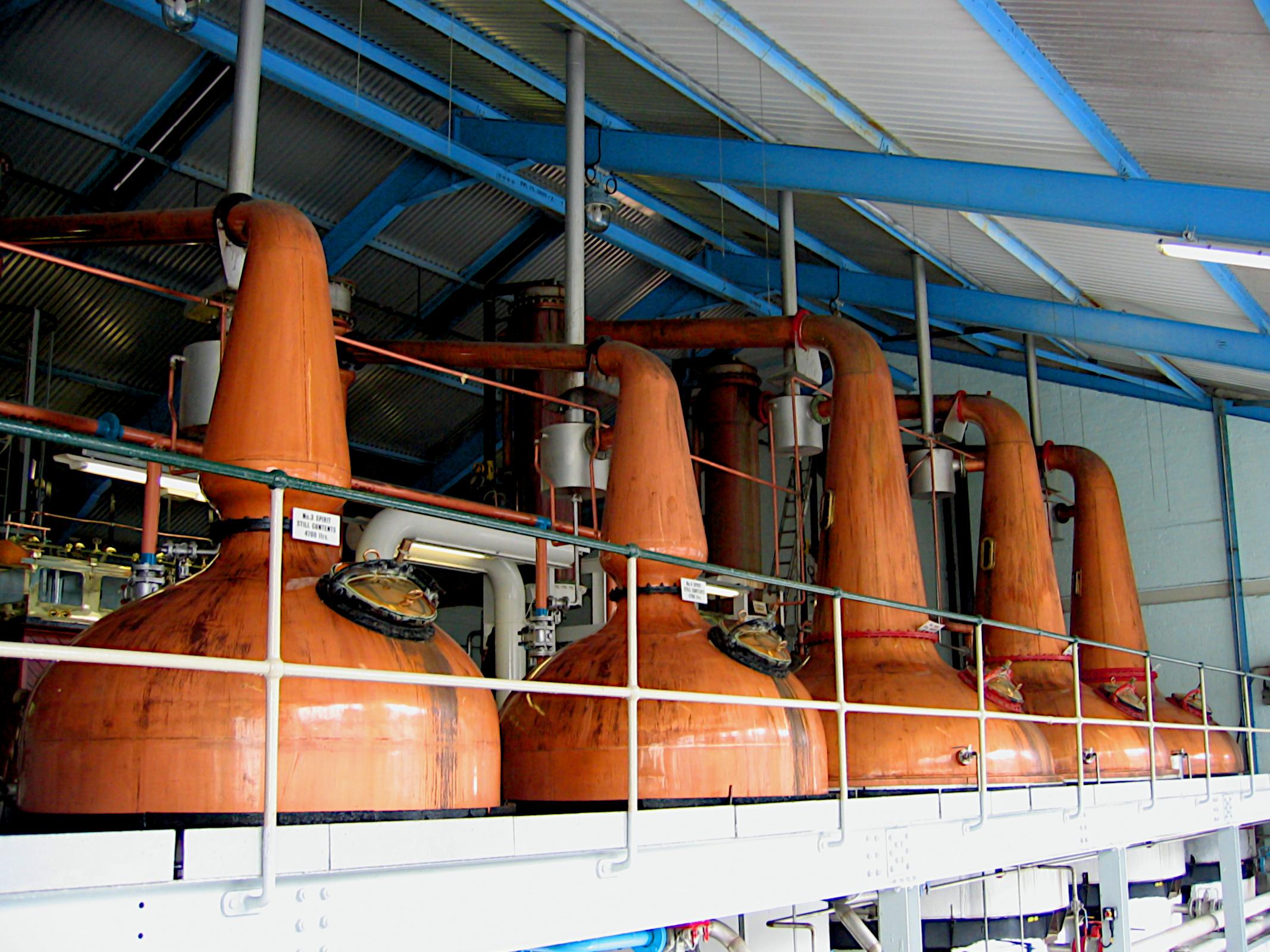 In einer Halle sind insgesammt fünf Brennblasen aus Kupfer zu sehen. Die drei hinteren sind etwas größer als die zwei vorderen. Alle haben einen hohen Hals, der weiter oben nach links abgeknickt ist.