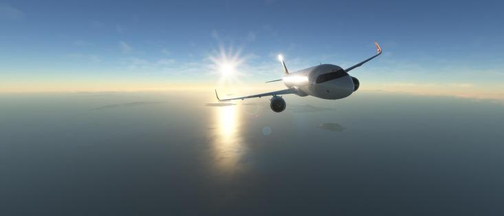 The image depicts a commercial airplane flying over a vast body of water, likely an ocean or sea, during what appears to be either sunrise or sunset. The sun is positioned low on the horizon, casting a warm glow and creating a lens flare effect in the sky. The airplane is captured in mid-flight, with its landing gear retracted, suggesting it is at cruising altitude. The aircraft has a sleek design, with a white fuselage and dark-colored tail. The water below reflects the sunlight, adding to the serene and picturesque quality of the scene. The horizon is visible in the distance, with a faint outline of land or islands on the horizon. The overall atmosphere of the image is calm and tranquil, evoking a sense of freedom and adventure associated with air travel.