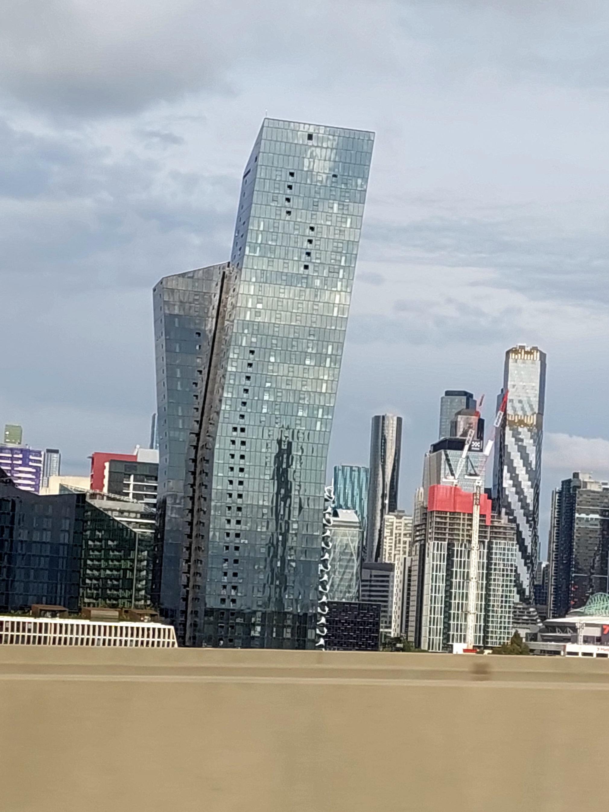 Ein sich scheinbar nach rechts beugendes Hochhaus vor weiteren Hochhäusern 