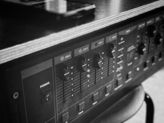 Detailaufnahme eines Lichttechnik-Pultes samt einiger Schieberegler in S/W.