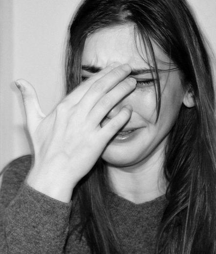 black and white photograph of a sad person with long hair with their hand in front of their face