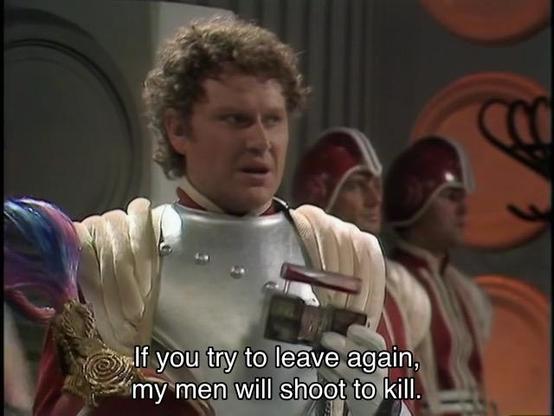 Peter Davison episode. Colin Baker’s Doctor is standing in the TARDIS, in Gallifreyan soldier garb, which doesn’t involve the giant collar, but instead a metal chest plate and fluffy white and colorful purple shoulders. He’s in the TARDIS, lights down and dark, holding a piece of the console. Caption reads, “IF you try to leave again, my men will shoot to kill.” Wait, no, it’s just Commander Maxil, who’s also played by Colin Baker.