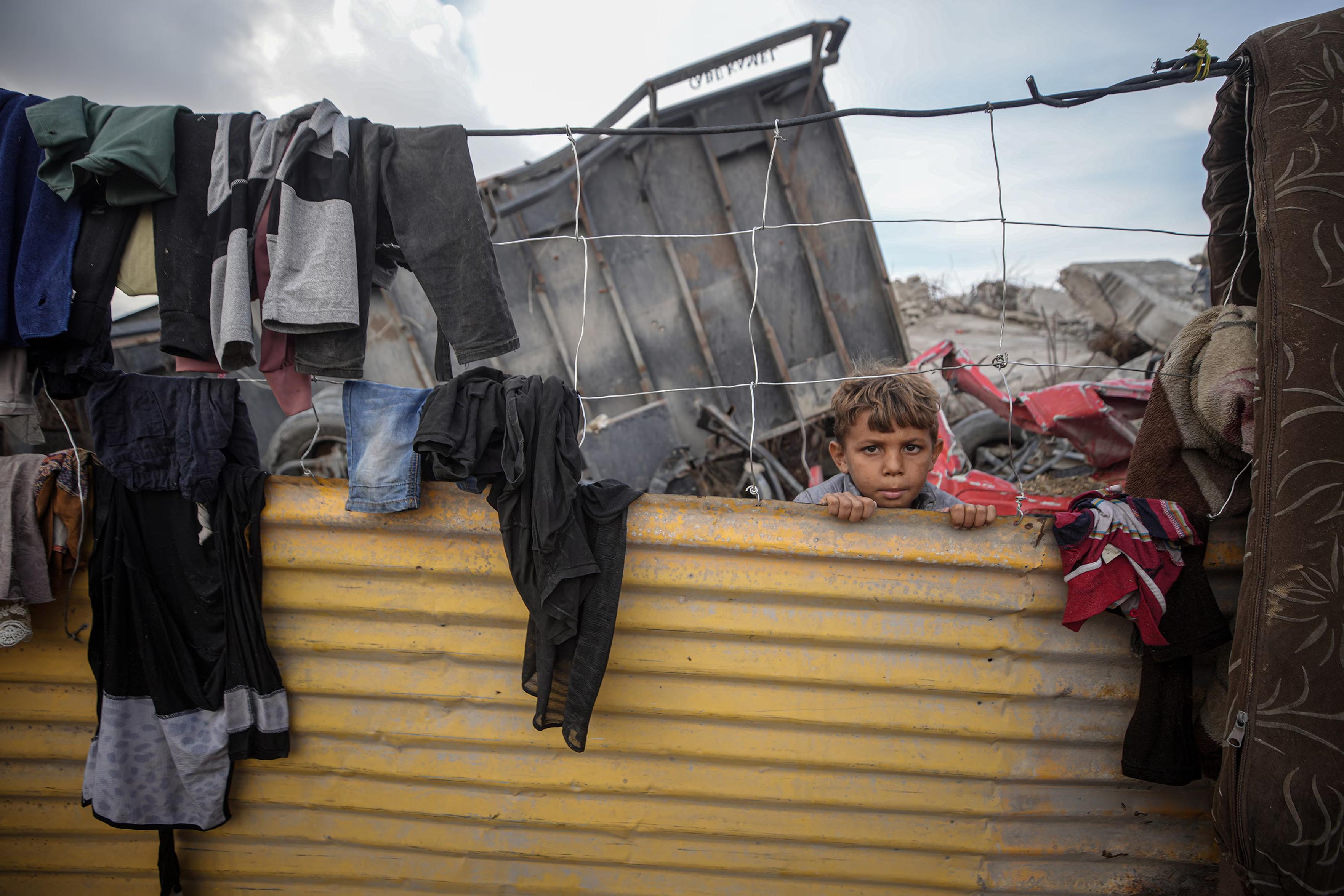 A child stares out from a makeshift shelter.