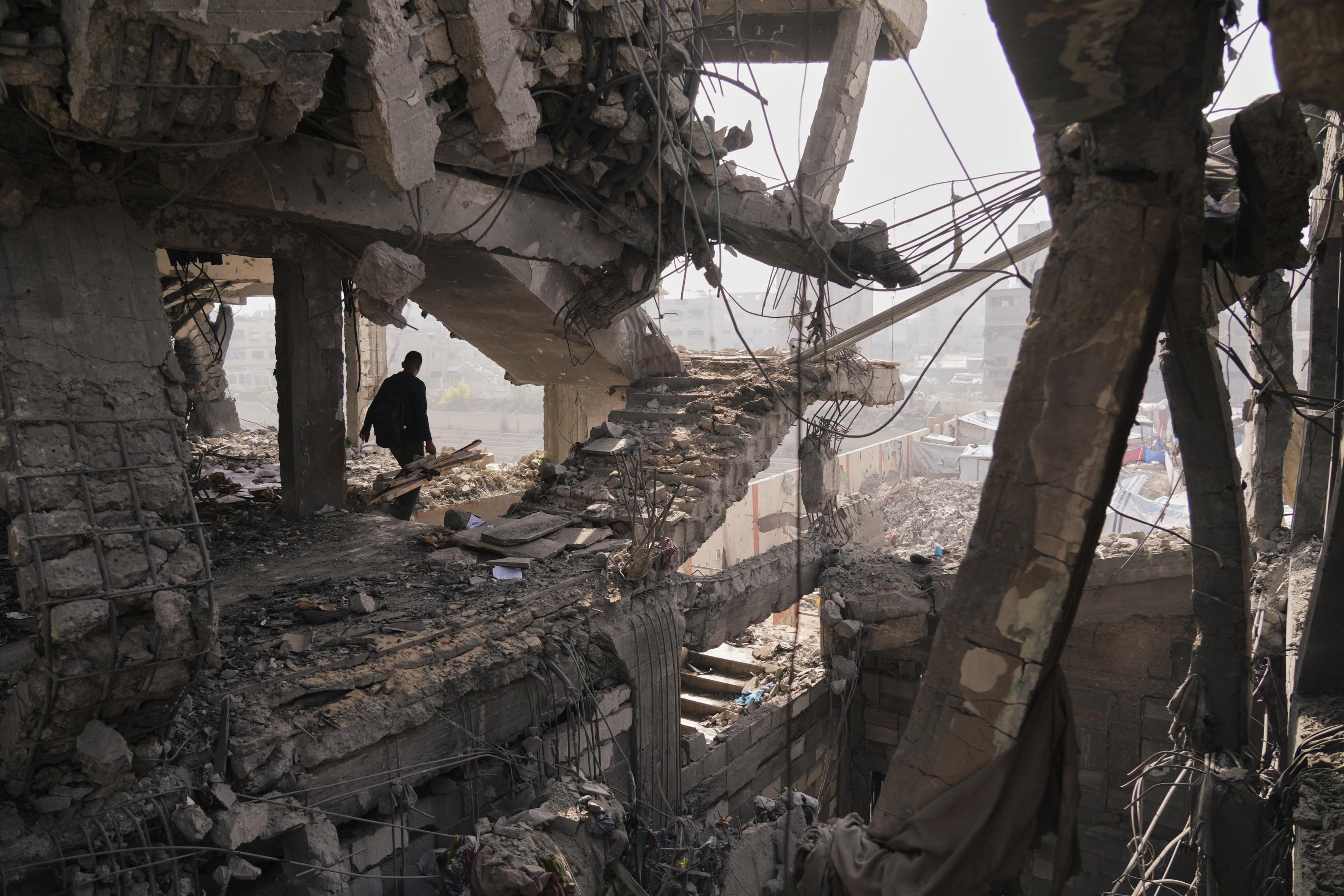 People inspect the ruins of building a day after an Israeli strike, with a staircase ending abruptly mid-air.