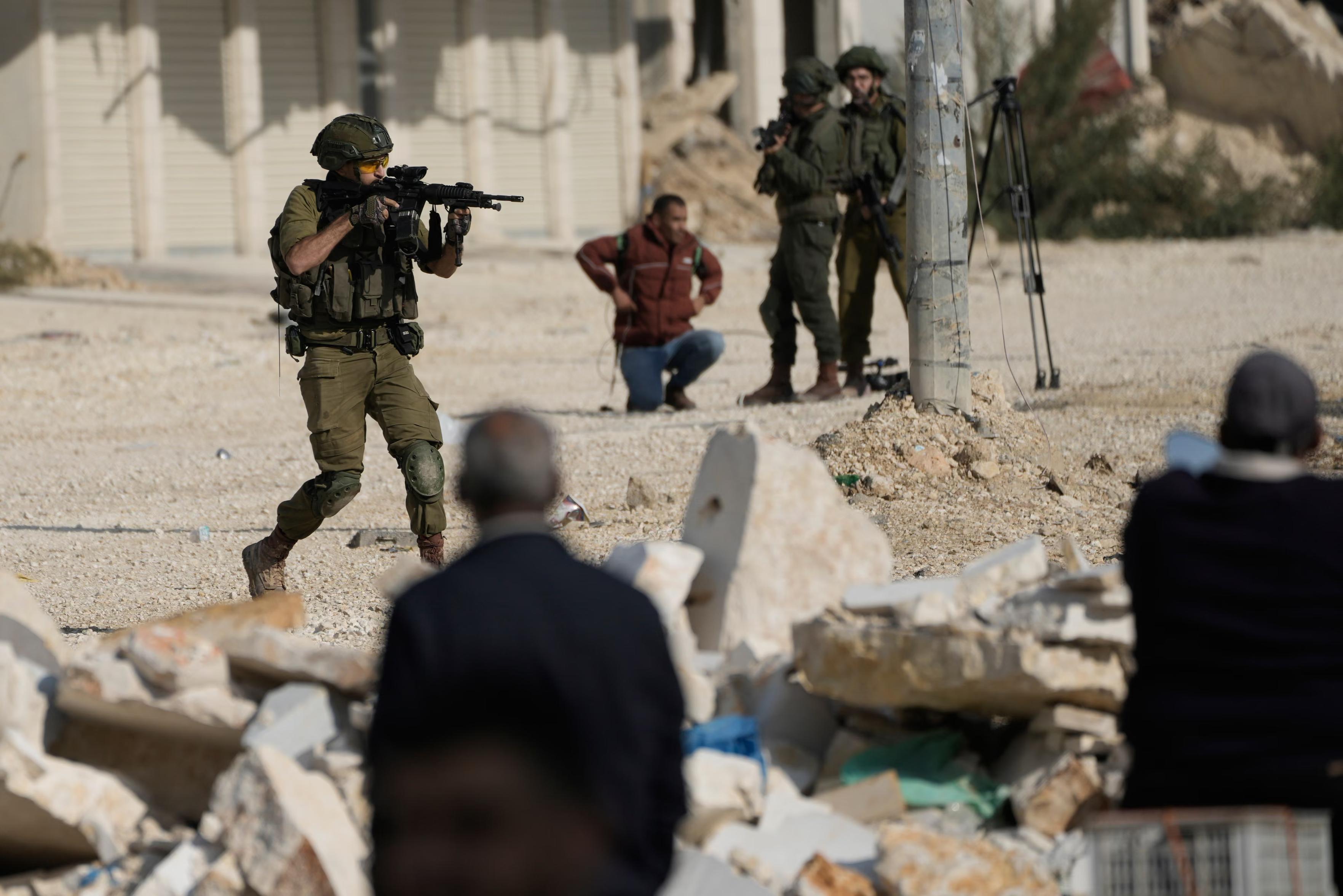 An Israeli soldier aims his weapon at protesters.