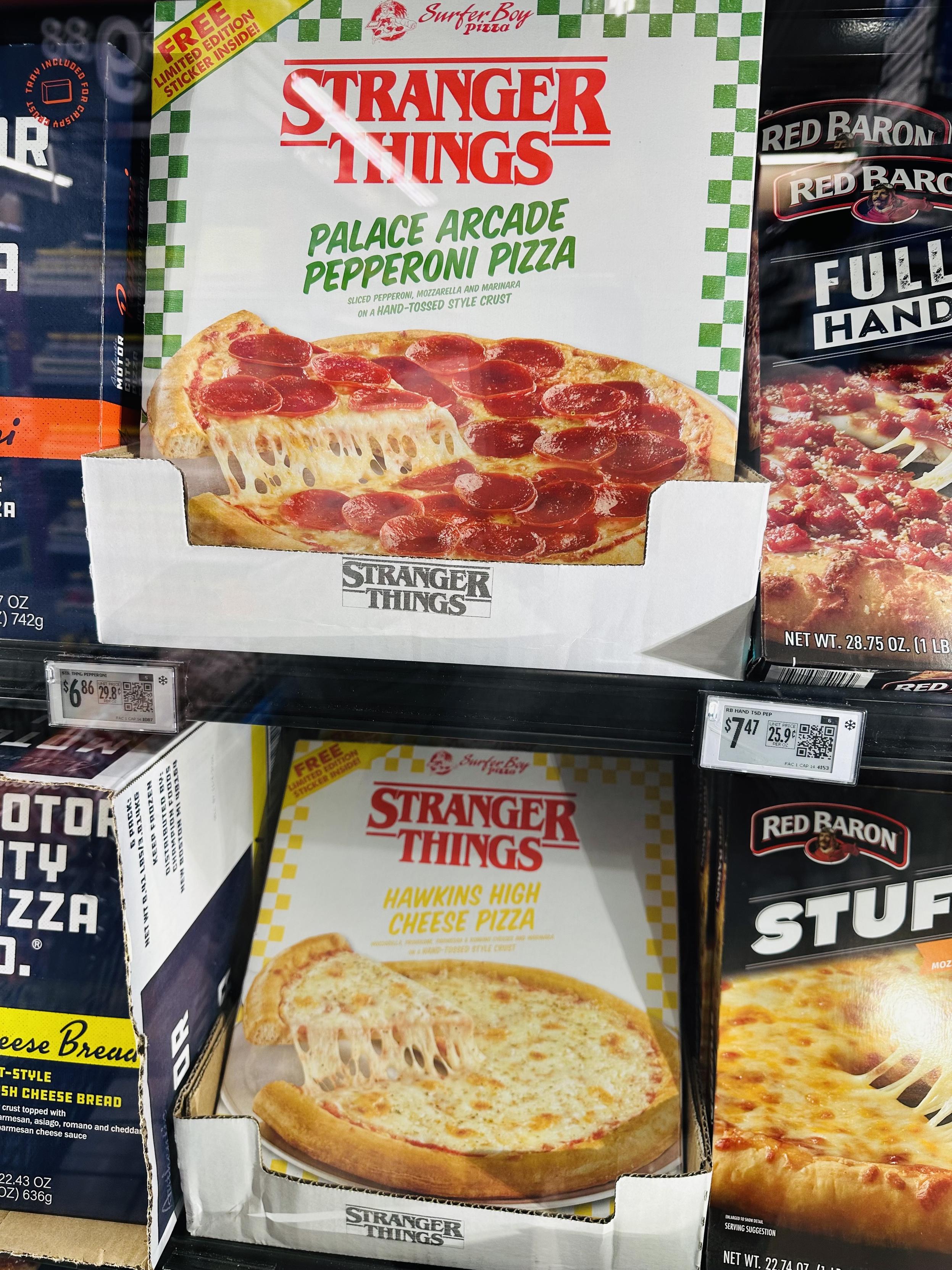 Boxes of Stranger Things frozen pizza at the grocery store - Arcade Palace Pepperoni Pizza and Hawkins High Cheese Pizza in retro-styled checkerboard boxes.