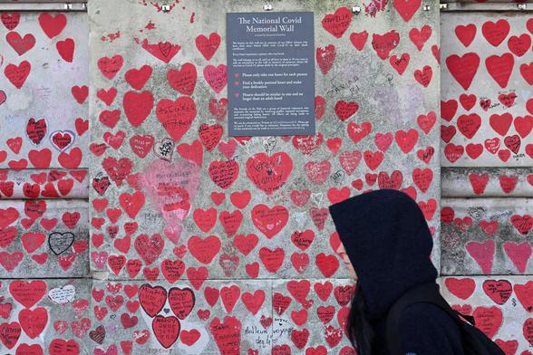 A person walks past the National Covid Memorial Wall covered by red hearts.