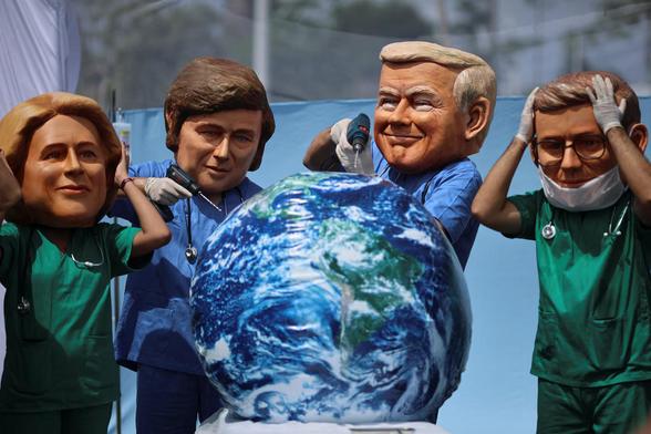 Oxfam activists wearing big head masks depicting world leaders stage a mock emergency room scene symbolizing a dying Planet Earth.