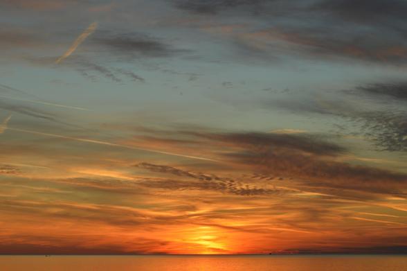 A sunset on a Great Lake in Ontario, the blue highlights against an orange mid sky, reflecting along the water