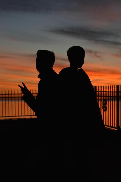 Silhouette image of two children against a red and orange sunset