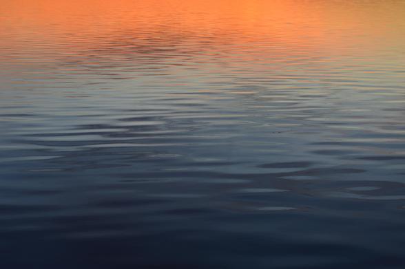 A calm lake front, a gradient of orange and blue