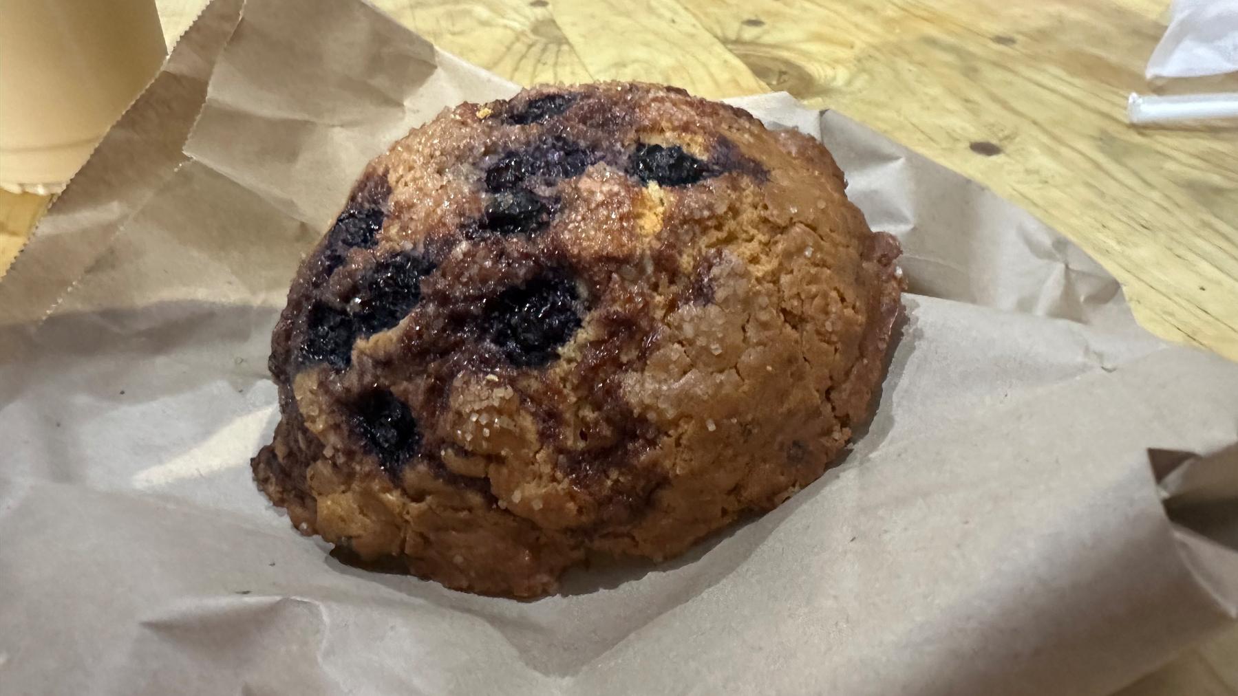 A big ol' blueberry scone on a paper bag. 
