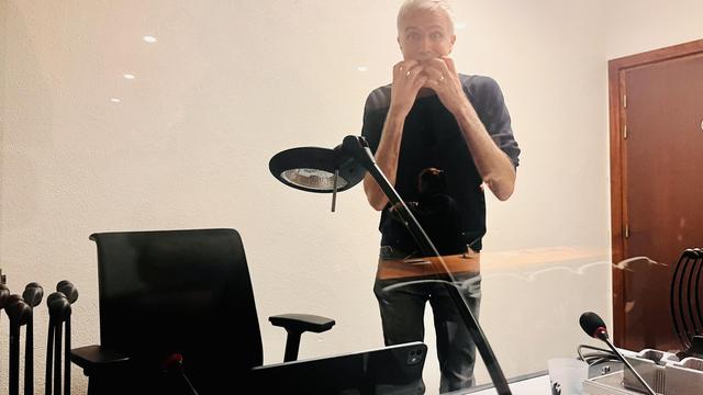 Un homme debout derrière un bureau mime le trac d’avant spectacle.