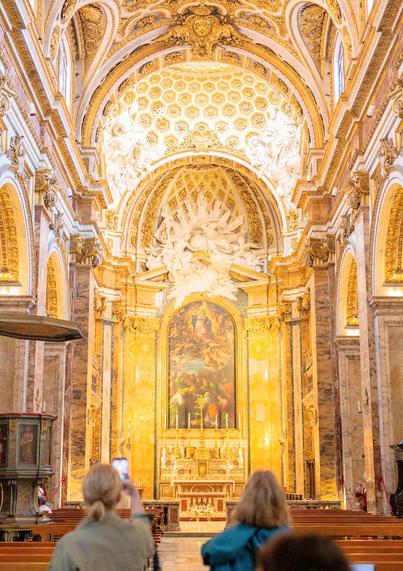 An Inside picture of a grand church with a very high decorated domed ceiling!*& The entire church is decorated with various different designs of colors of gold!*yellow!*bronze!*& White 