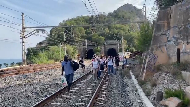 Passatgers de Rodalies caminant per la via, al Garraf, després de ser evacuats d'un tren avariat el 6 de juny (3CatInfo)