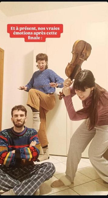 Une photo prise peu après la précédente. M est assis sur le sol, les bras croisés et fait une grimace mécontente. C "crie" et fait mine de casser un archet contre son genou levé. L s'apprête à exploser son violon sur le sol, le visage grimaçant. Sur l'image, le texte : "Et à présent, nos vraies émotions après cette finale"