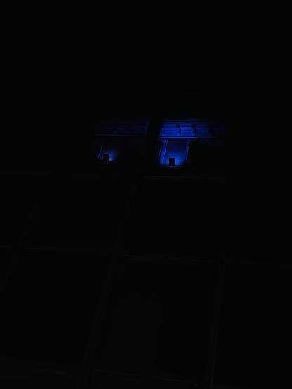 Reflejo de unas ventanas y algunas molduras, de color morado por la luz nocturna, en una fachada de cristal. El mismo lugar fotografiado de dos maneras diferentes, una con más luz y otra más negra.