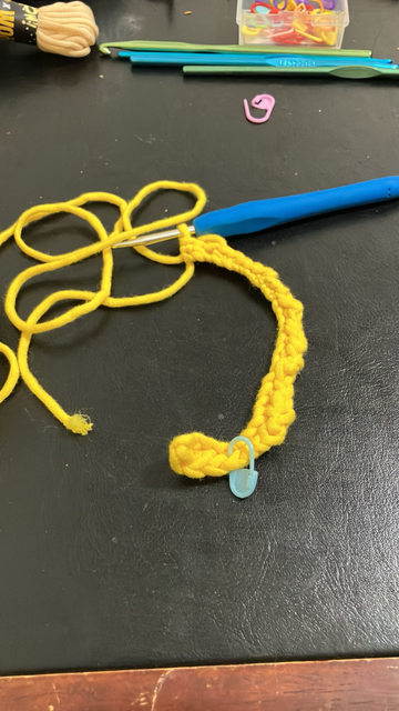 A crochet hook with some yellow yarn on it.