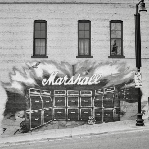 A black-and-white film photo. A large mural of a Marshall stack is featured on the side of an old building in downtown Austin, Texas. Sunday, November 16, 2025.
