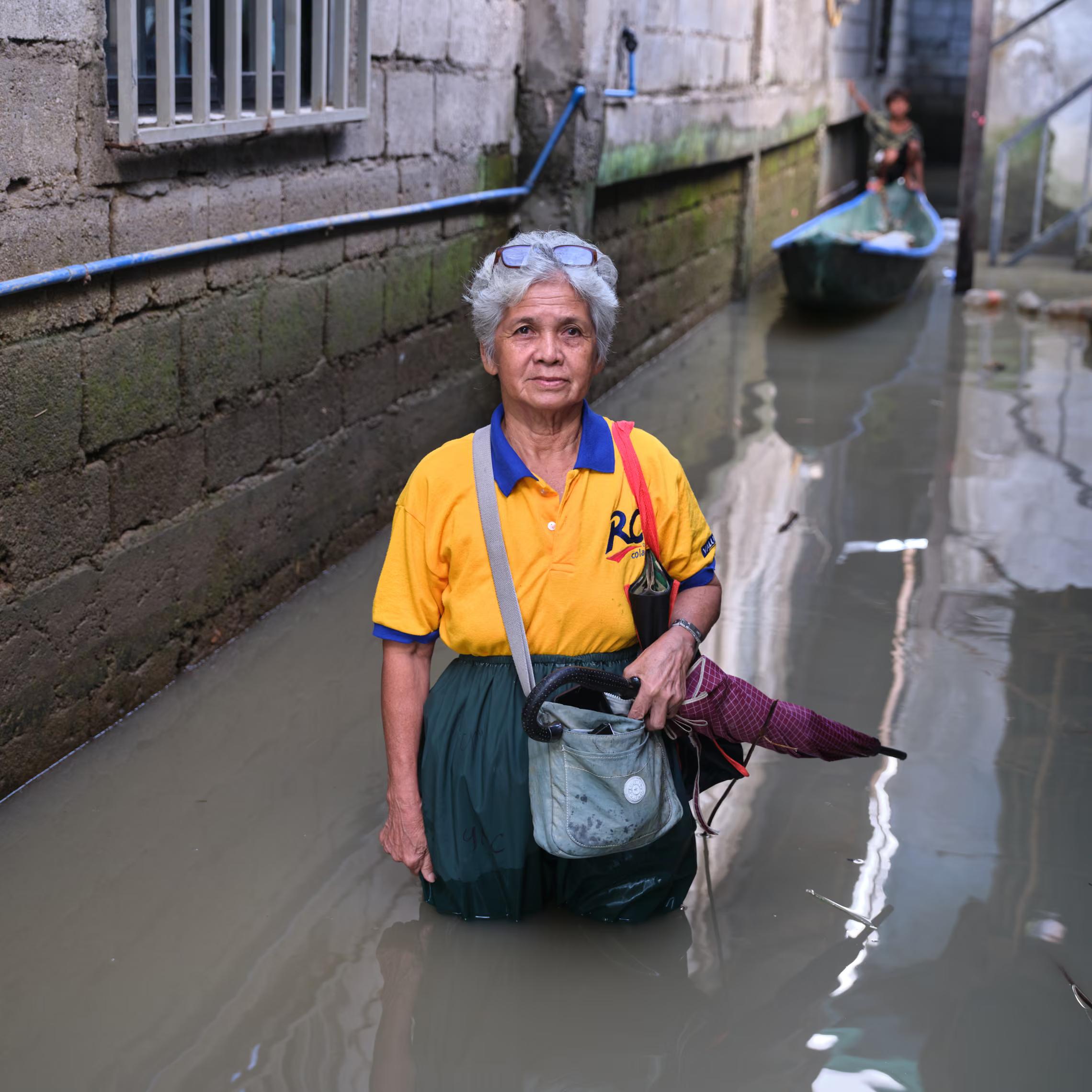 An elderly woman stands in a flooded street, with a boat behind her.
"Before, even though we got flooded, when the water disappeared, it was gone. Now, the water really doesn’t leave us. We’ve been like this for six months. If we could just move to a higher place, we would. But there’s no choice, nothing."
