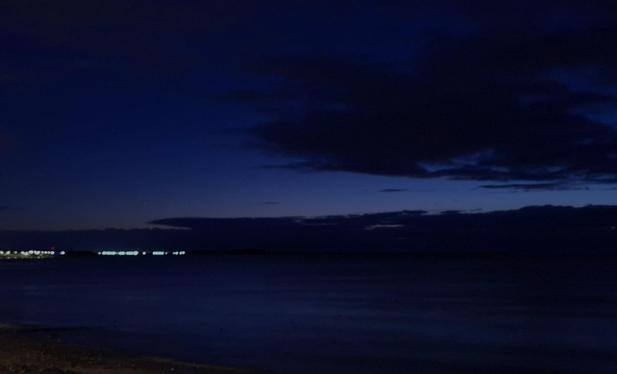 A fairly dark picture, probably a river at the front ( #RiverTay ), at the horizon at the left maybe some lights from houses. Clouds in a dark blie sky. Maybe a hint of sunlight, beginnings of dawn?