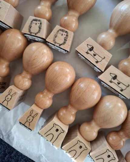 Mehrere Holzstempel, bedruckt mit einfachen Tierzeichnungen: Igel, Dackel, Hase und Bär.