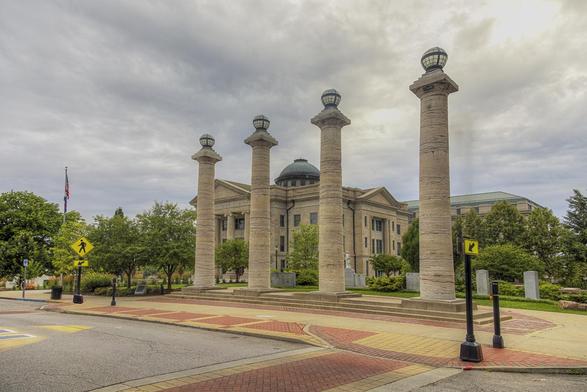 Four stone columns stand prominently in the foreground, framed by the historic Boone County Courthouse, with a domed roof in the background. 
