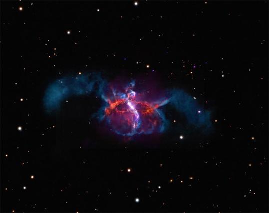 Multiple telescopes teamed up to capture an image that looks like a cozy sweater with fuzzy arms. X-rays from Chandra and ESA’s XMM-Newton (purple), optical light data from Hubble and the Very Large Telescope in Chile (orange, red, and violet), and an optical image from astrophotographer Bob Fera (deep blue) combine to reveal R Aquarii. Nestled within the cozy ‘body’ of R Aquarii is a pair of stars where a white dwarf is pulling material from a much larger red giant companion. When enough material accumulates on the surface of the white dwarf, it triggers an outburst that sends a jet out into space. Over time, these jets twist and loop around each other weaving the structure seen today.
Credit: X-ray: NASA/CXC/SAO; ESA/XMM-Newton; Optical HST: NASA/ESA/STScI; Optical Ground: Deep Space Remote observatories/B. Fera; ESO/VLT; Image Processing: NASA/CXC/SAO/L. Frattare