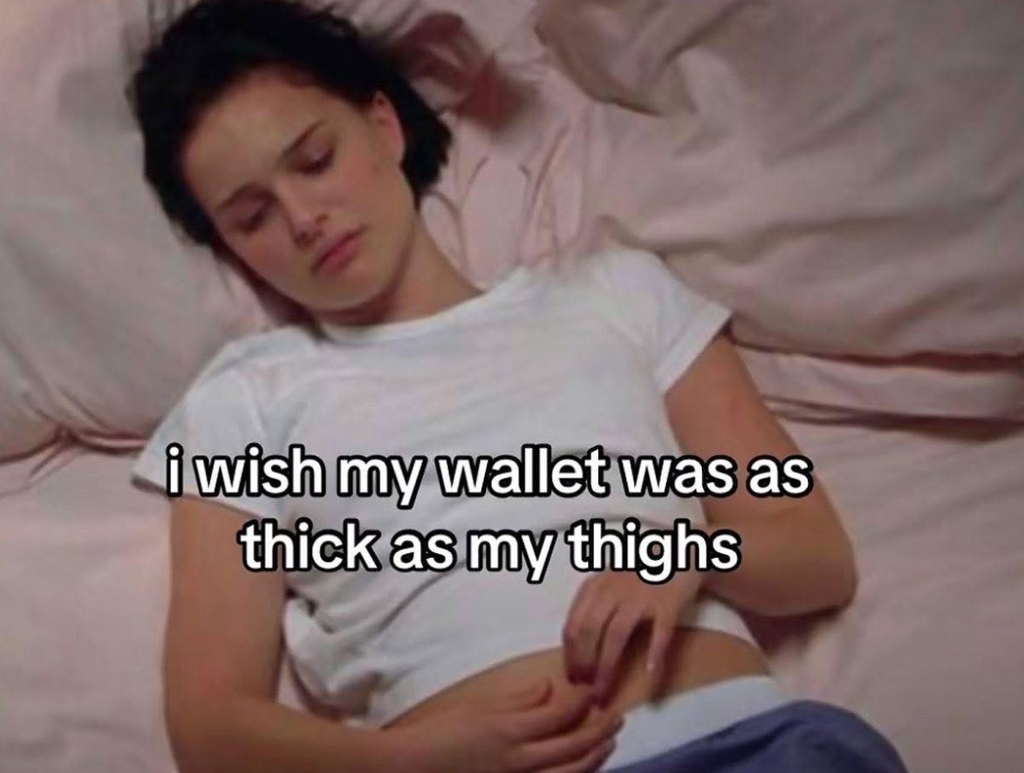 A meme featuring a still image of actress Natalie Portman lying in bed, resting her head on a pink pillow and wearing a white t-shirt and blue bottoms. Her eyes are half-closed, giving her a look of resignation or weariness. She is holding her hands loosely on her stomach. White text is overlaid on the lower half of the image, reading: "i wish my wallet was as thick as my thighs."