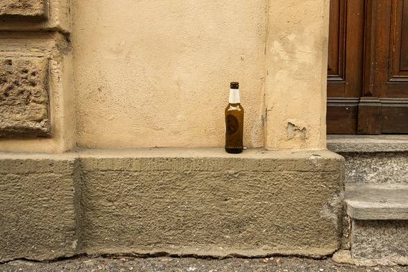 Eine leere Bierflasche steht auf einem Haussims. 