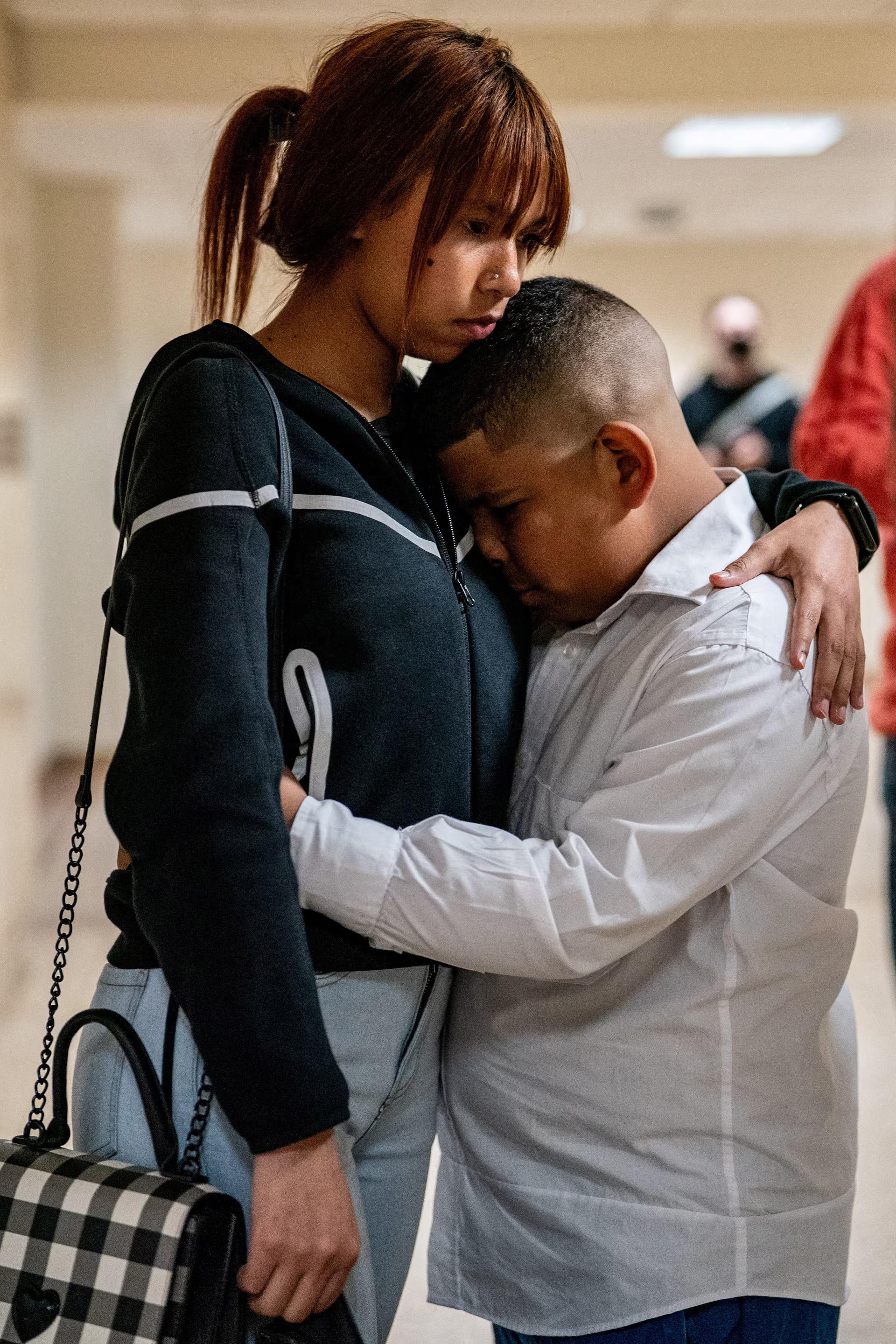 A child of a detained migrant mother weeps hugging his mother.