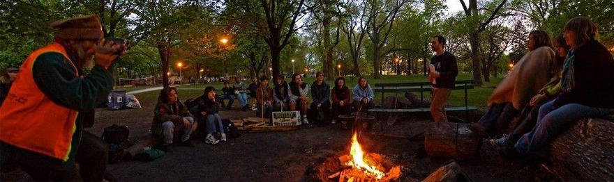 make conferences memorable: a photograph of people around a campfire with a man telling a story. Photo attribution: Flickr user dpnsan